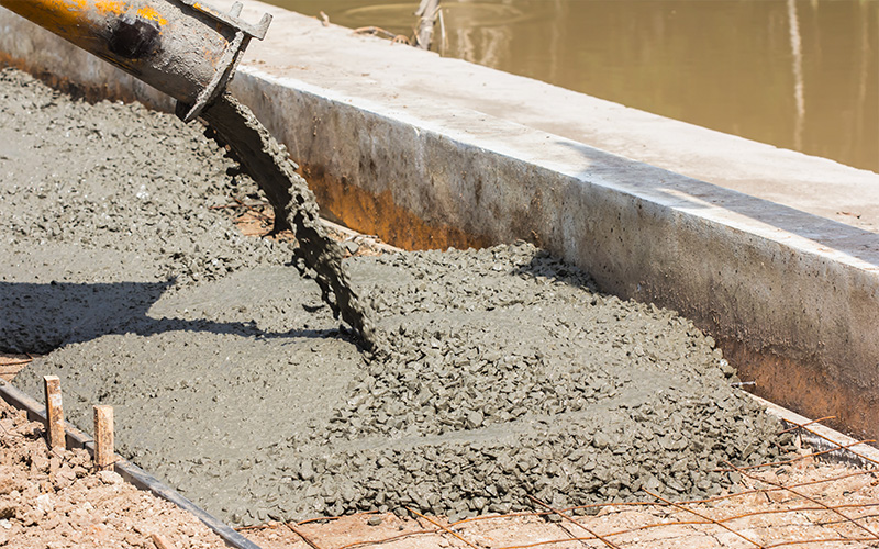 Construction worker smoothing a poured concrete foundation slab.