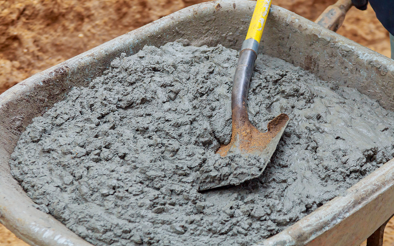 Wheelbarrow-filled-with-wet-concrete-mixture-and-a-shovel