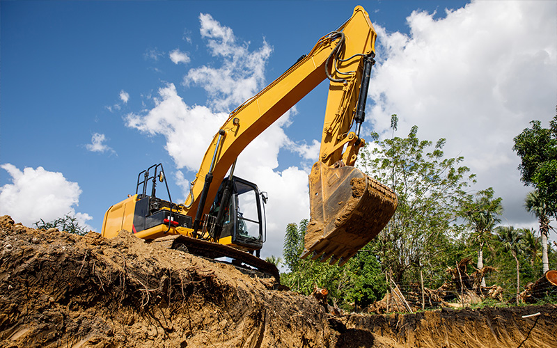 Large yellow excavator digging earth at a construction site.